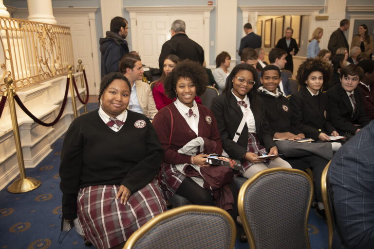 A group of students are seated at a speaking event.