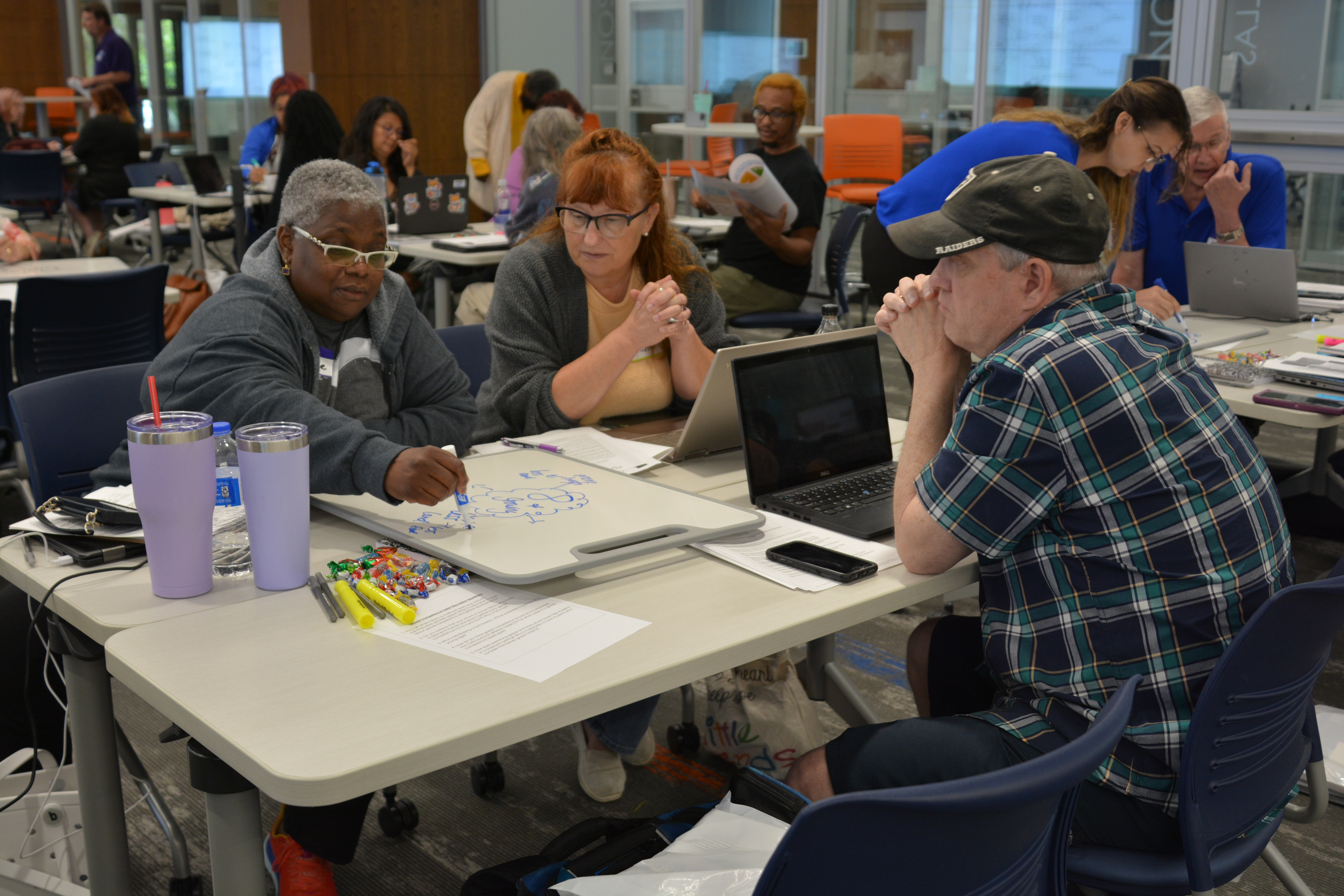 A group of teachers work together at a project table.