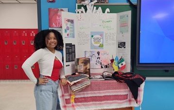 A student stands beside a presentation posterboard.