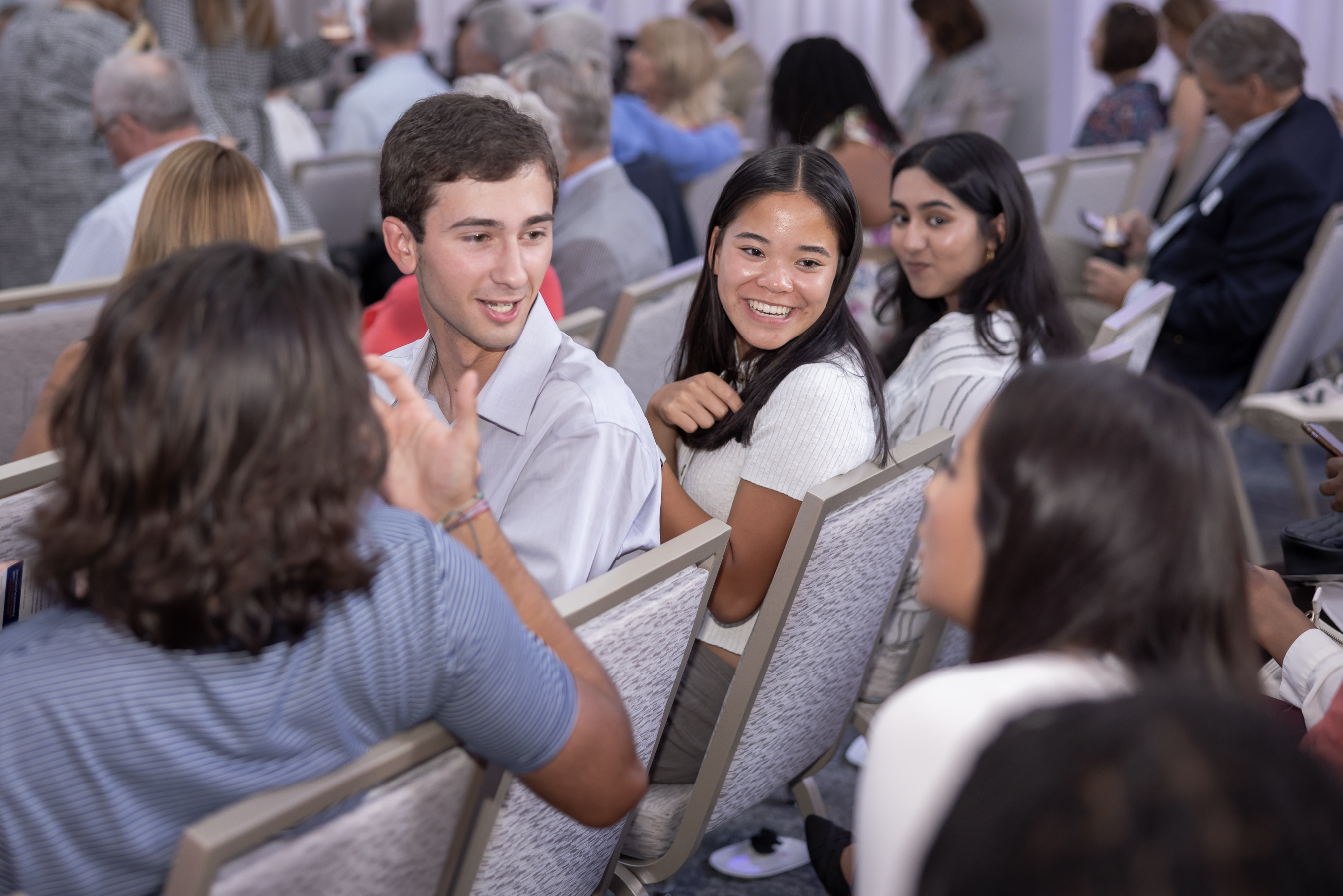 Students sitting in audience, chatting before a speaker event