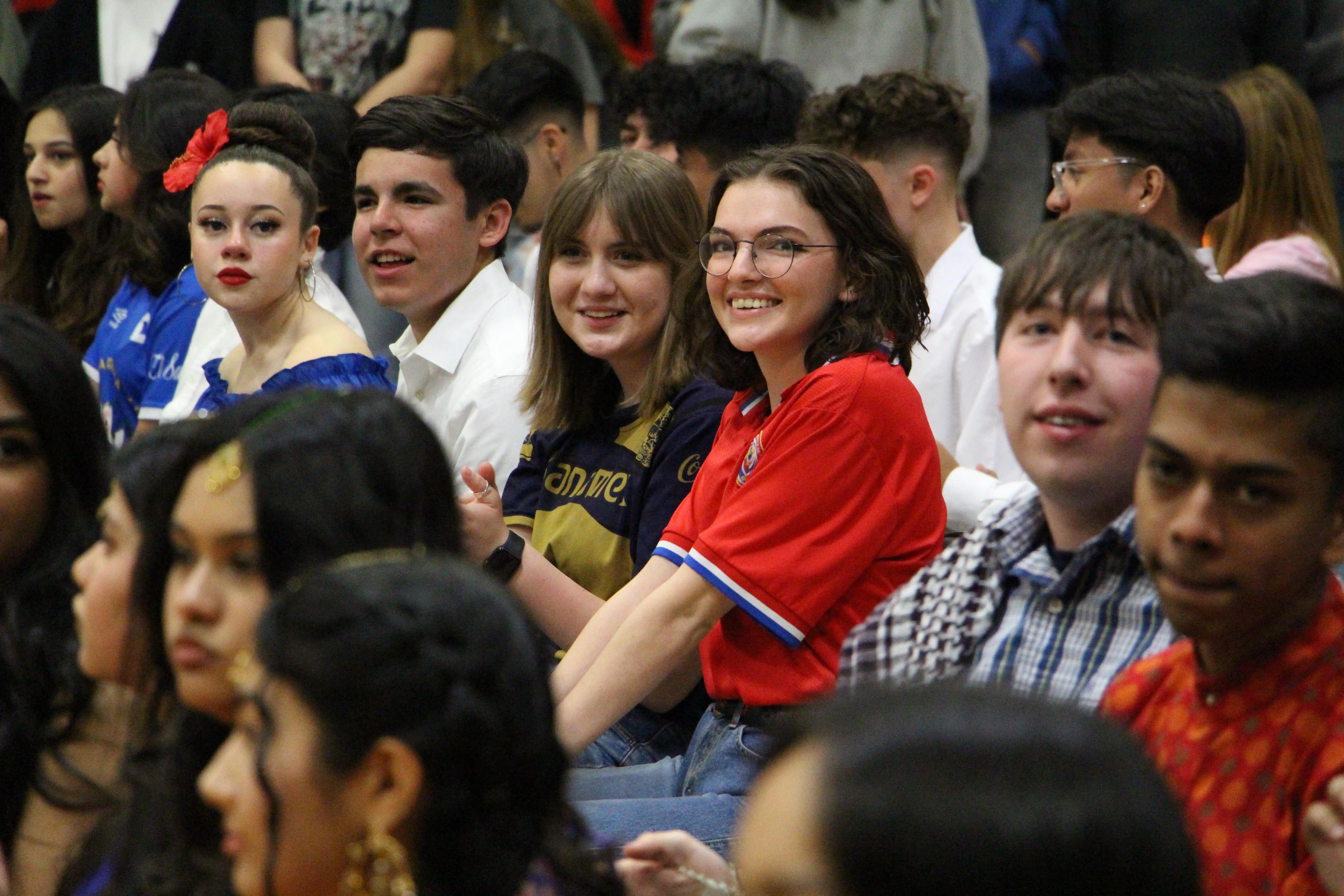 Seated students smile in the stands of an event.