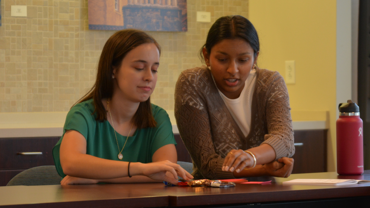 Two students sitting at a table looking at something on the desk